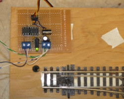 The very first MRServo prototype, hand-wired on a piece of perf board with a demo turnout on a stand.